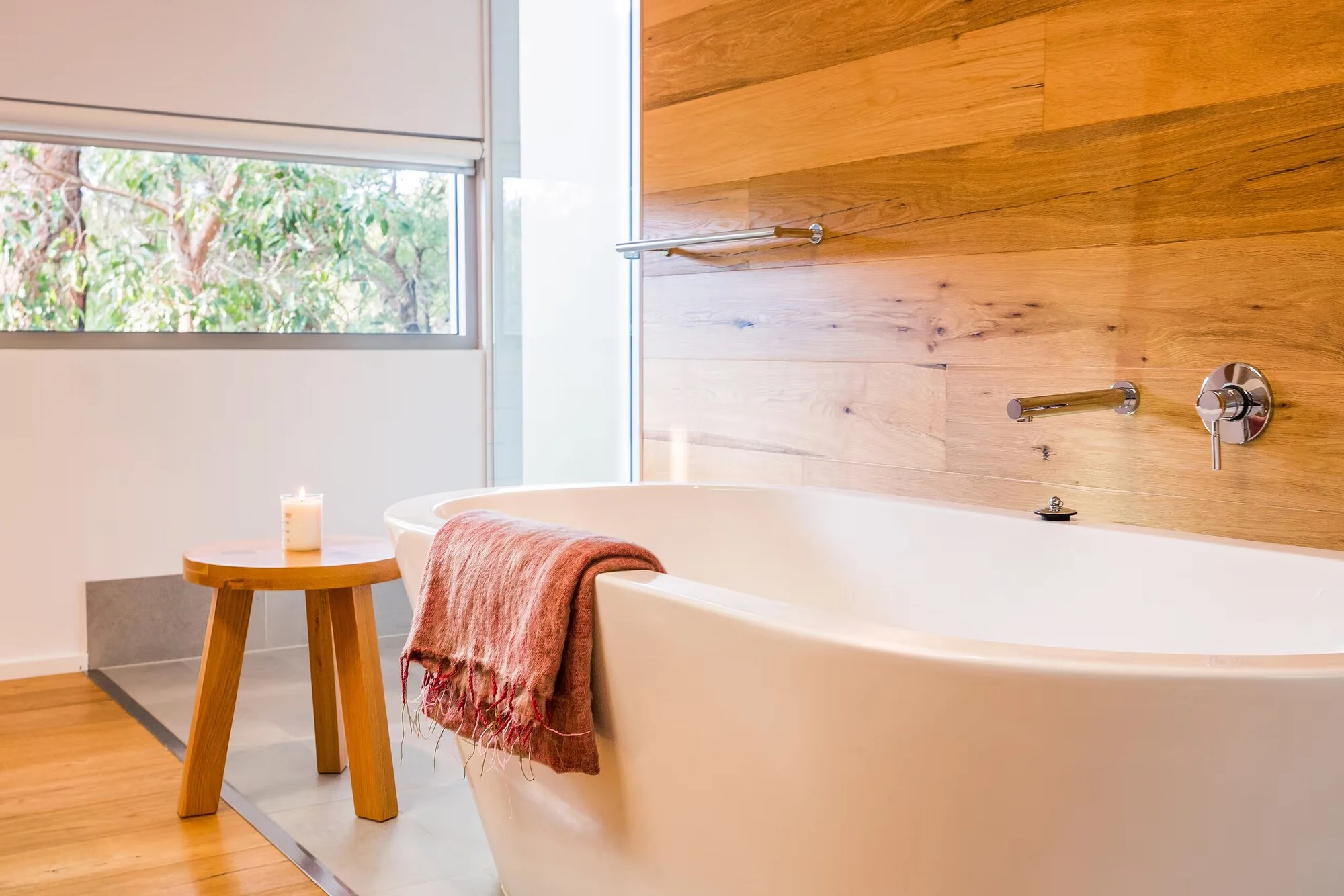 A freestanding bathtub in Injidup Sanctuary's ensuite with timber finishes and a window overlooking native greenery