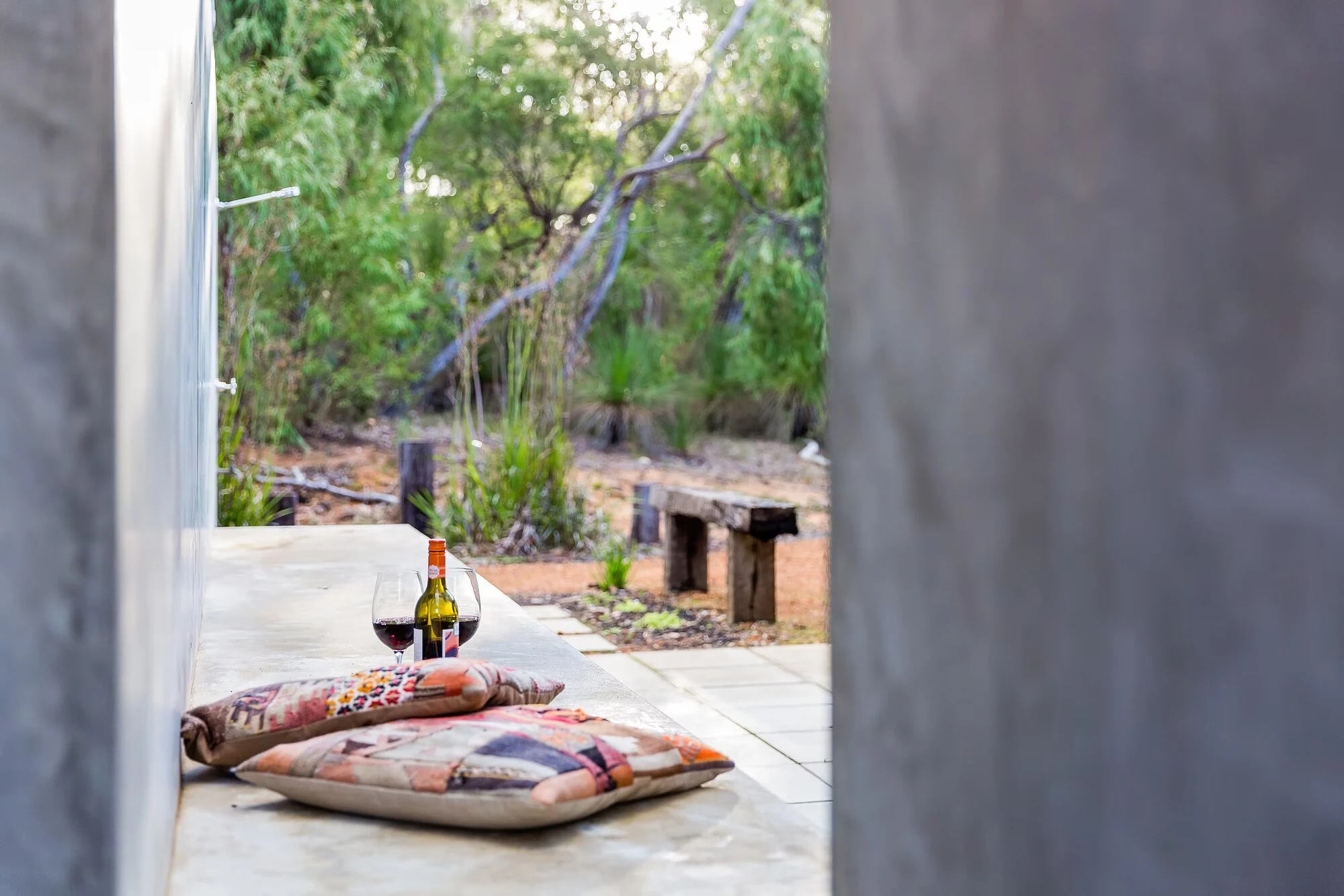 A sheltered seating nook at Injidup Sanctuary with cushions and views into native bushland