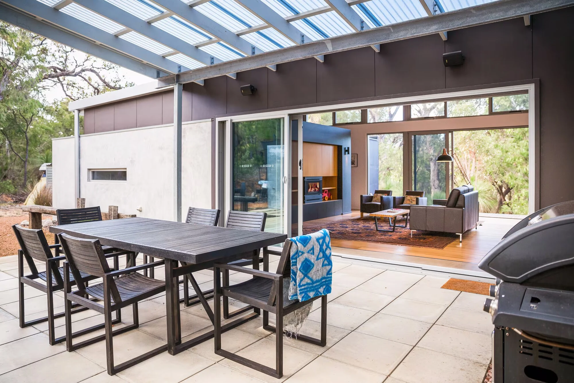 Injidup Sanctuary's covered outdoor dining area with a barbecue and sliding doors to the lounge