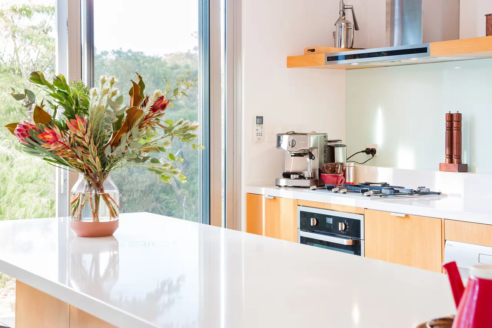 A close-up of Injidup Sanctuary's kitchen island with flowers, an espresso machine and a gas cooktop
