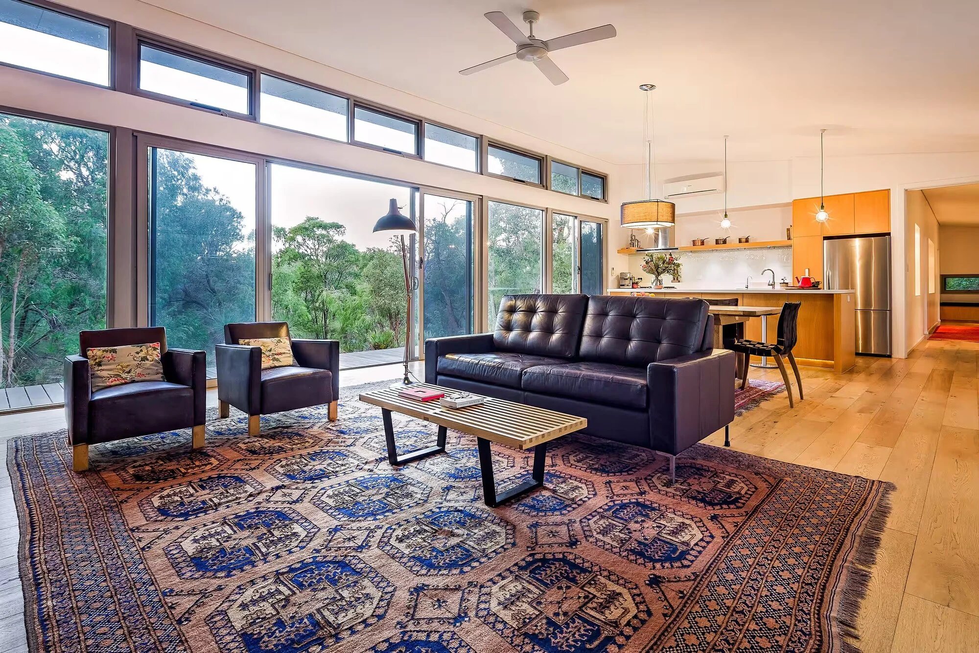 Injidup Sanctuary's lounge with leather seating, patterned rugs and expansive windows to the native bush