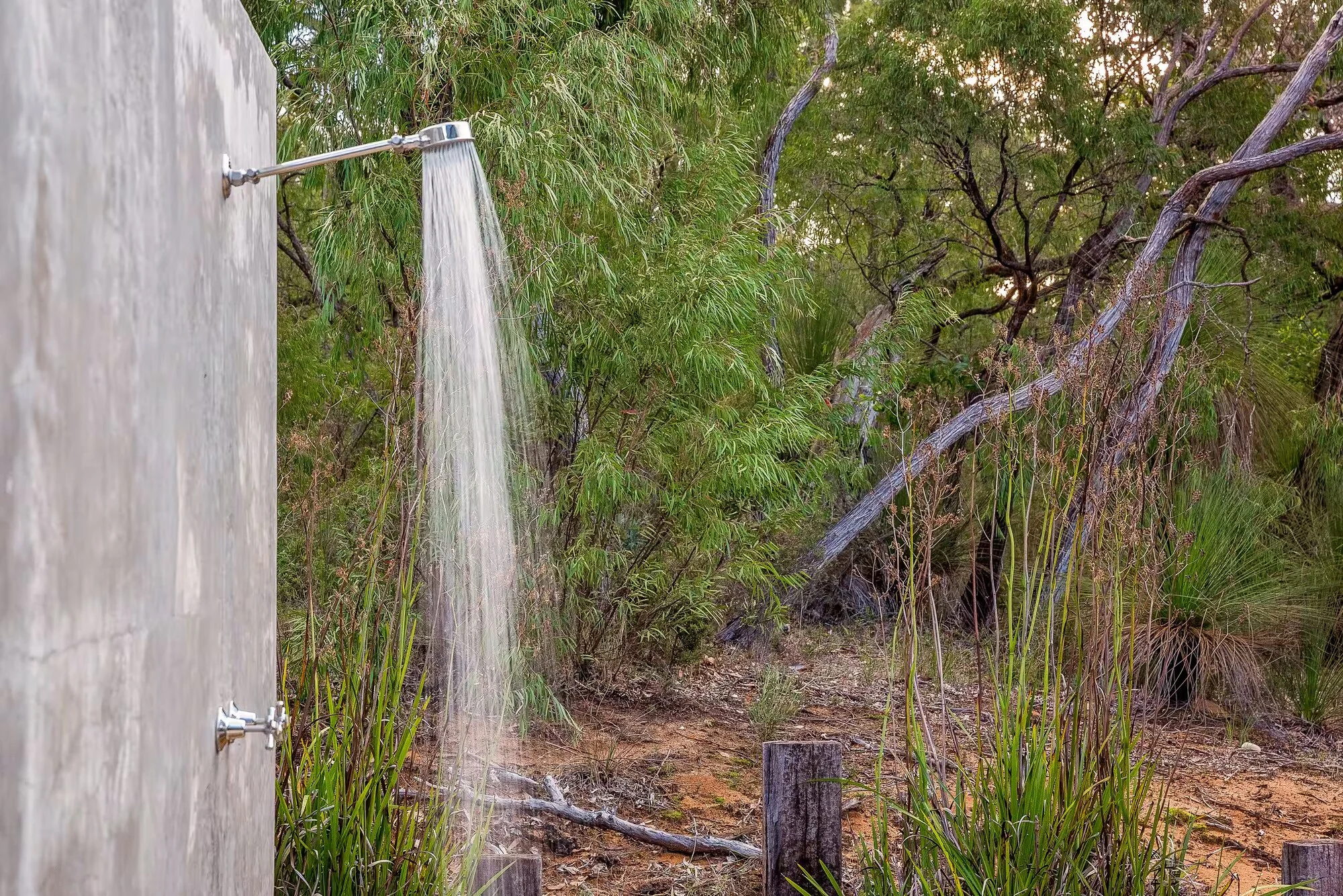 Injidup Sanctuary's outdoor shower beside native trees and garden plantings