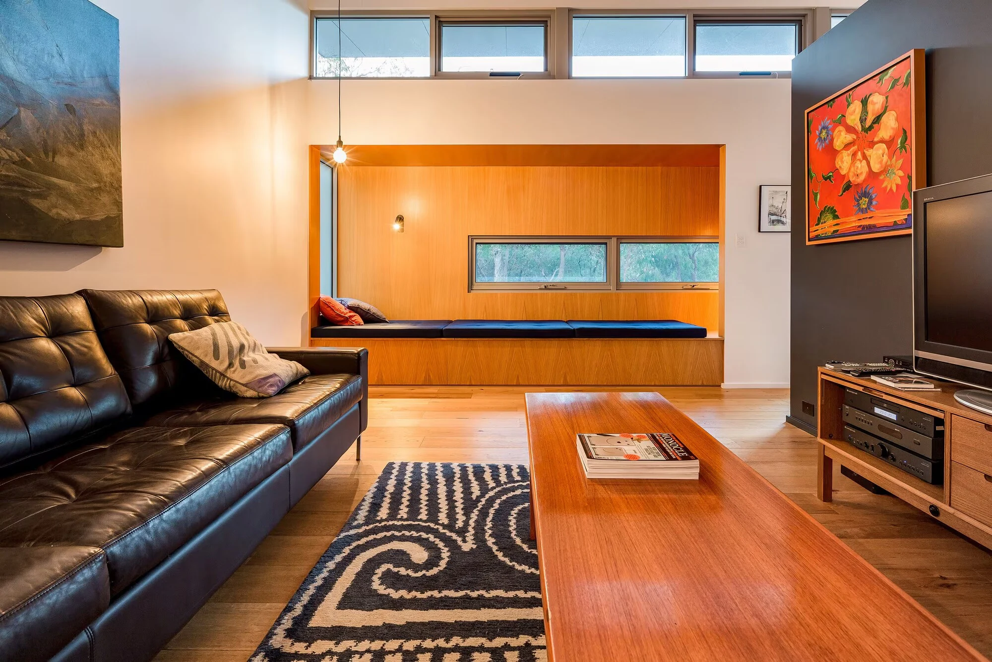 A second lounge at Injidup Sanctuary with leather seating, a television and a built-in timber window seat