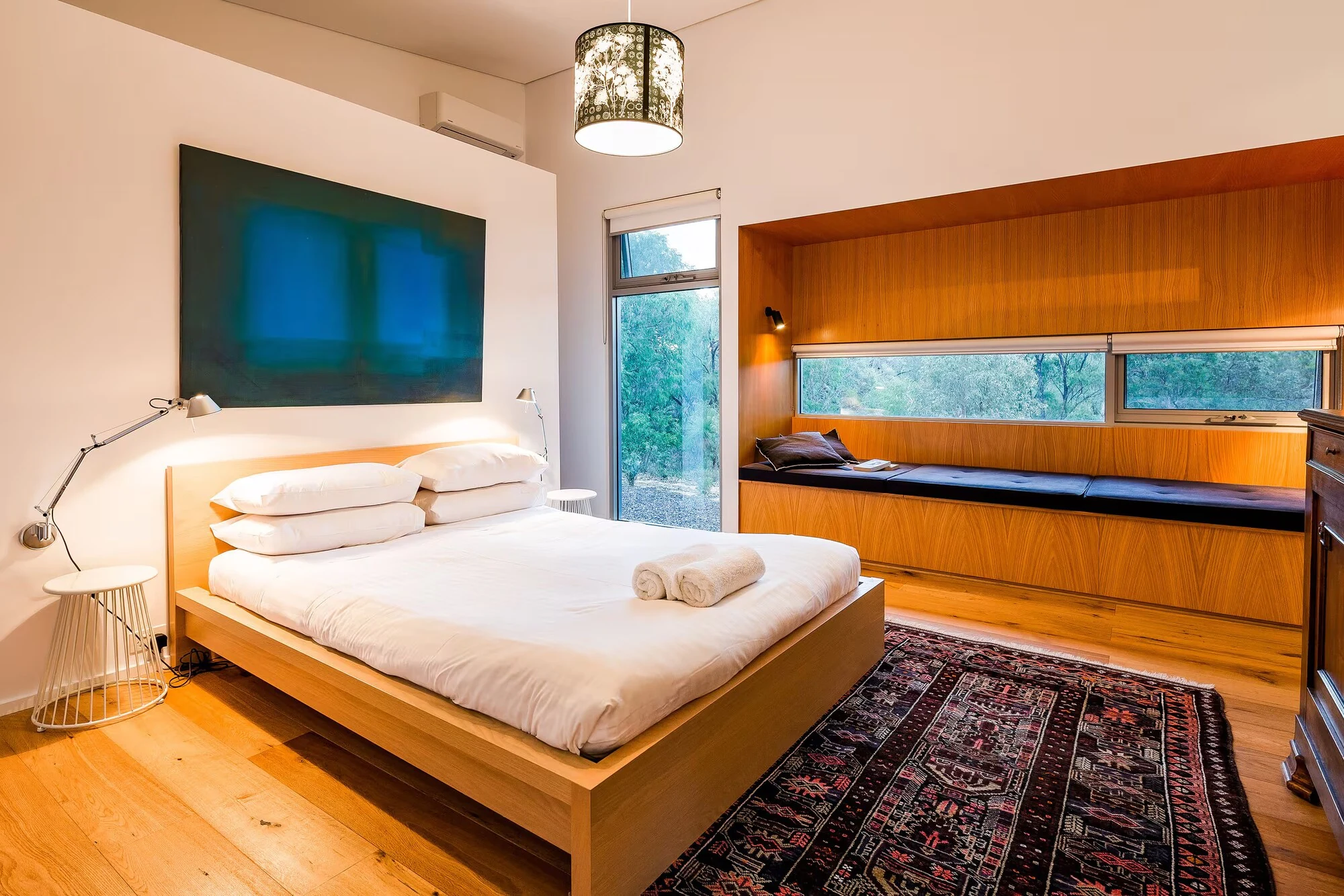 A bedroom at Injidup Sanctuary with original artwork and a timber window seat overlooking the bush