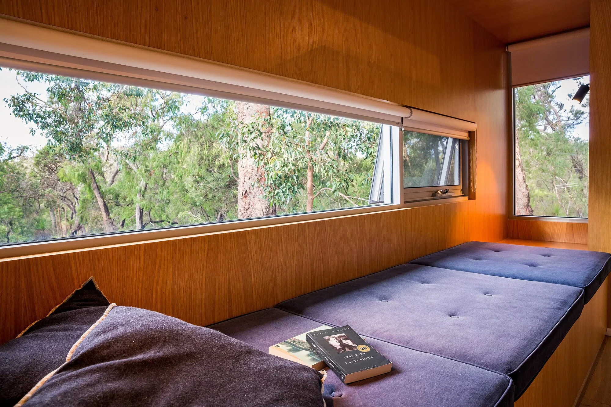 A cushioned timber window seat at Injidup Sanctuary overlooking native bushland